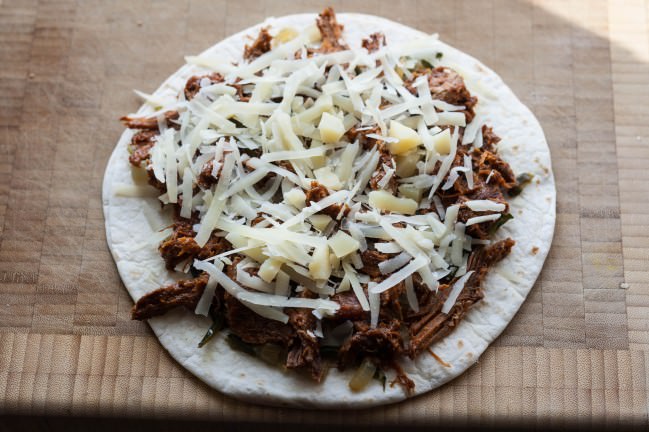 quesadilla layered with onions peppers pulled pork and cheese