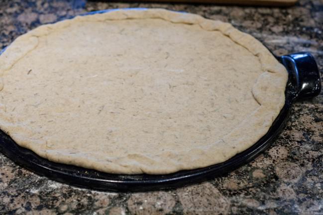 rolled out pizza dough on stone